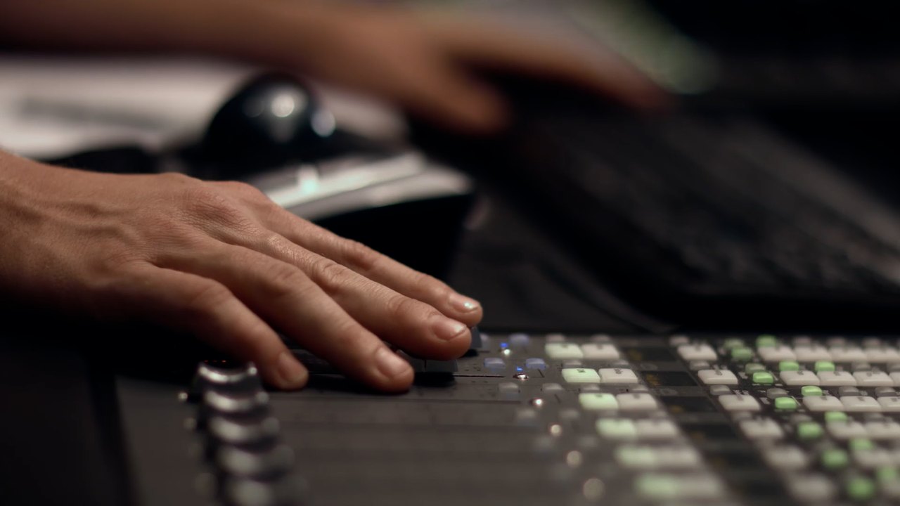 Post production — hands riding an audio mixing console